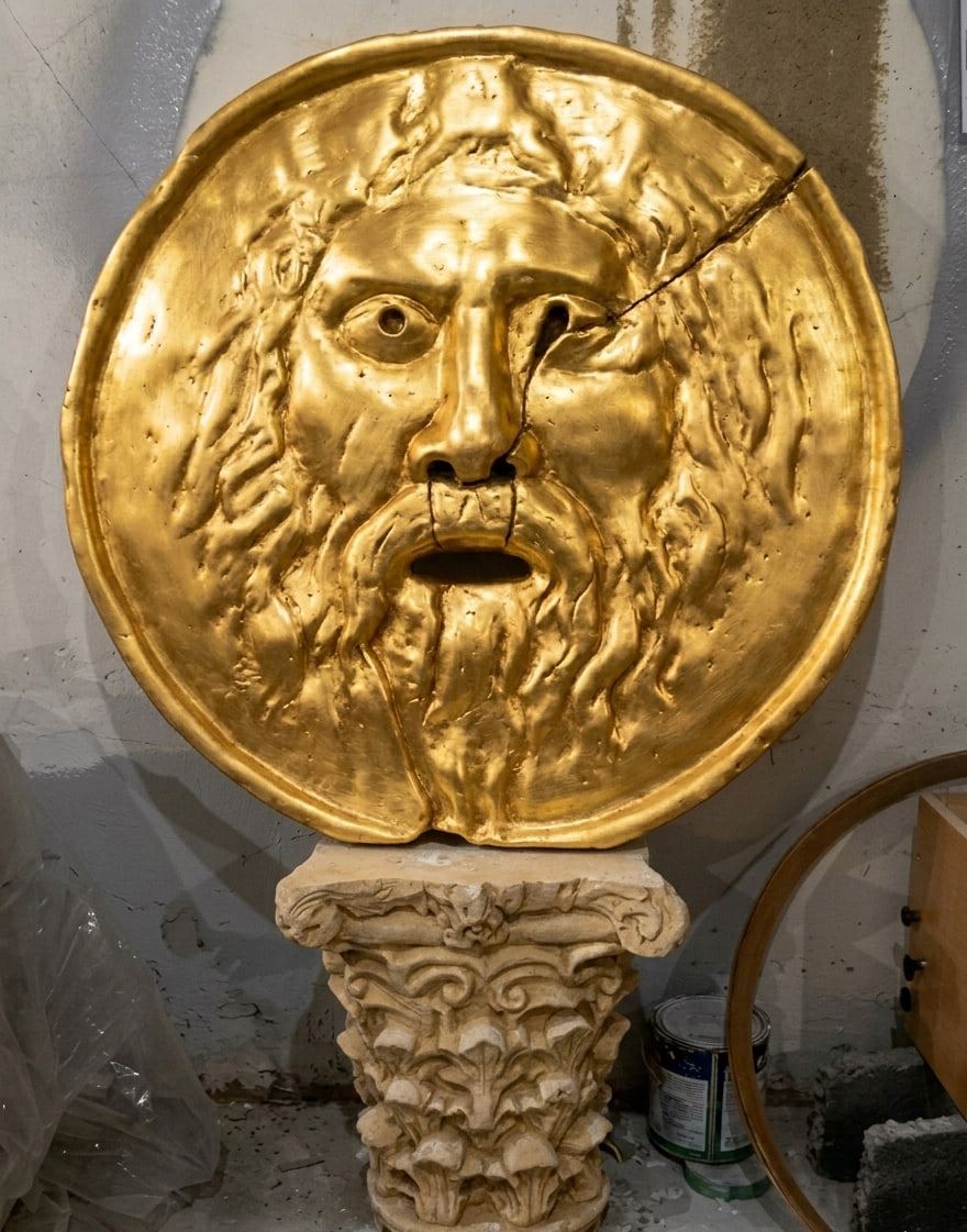 Relieve de la Bocca della Verità con baño dorado sobre un capitel, en el taller.