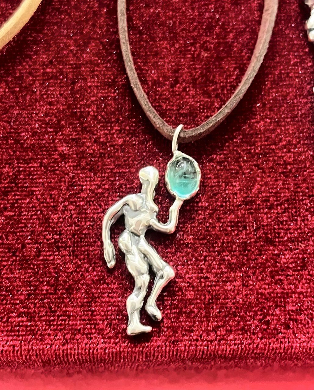 Colgante de plata con forma de bailarina y una aguamarina, sobre terciopelo rojo.