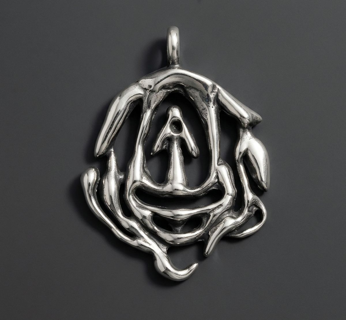 Colgante de plata con un rostro abstracto sobre fondo gris oscuro.