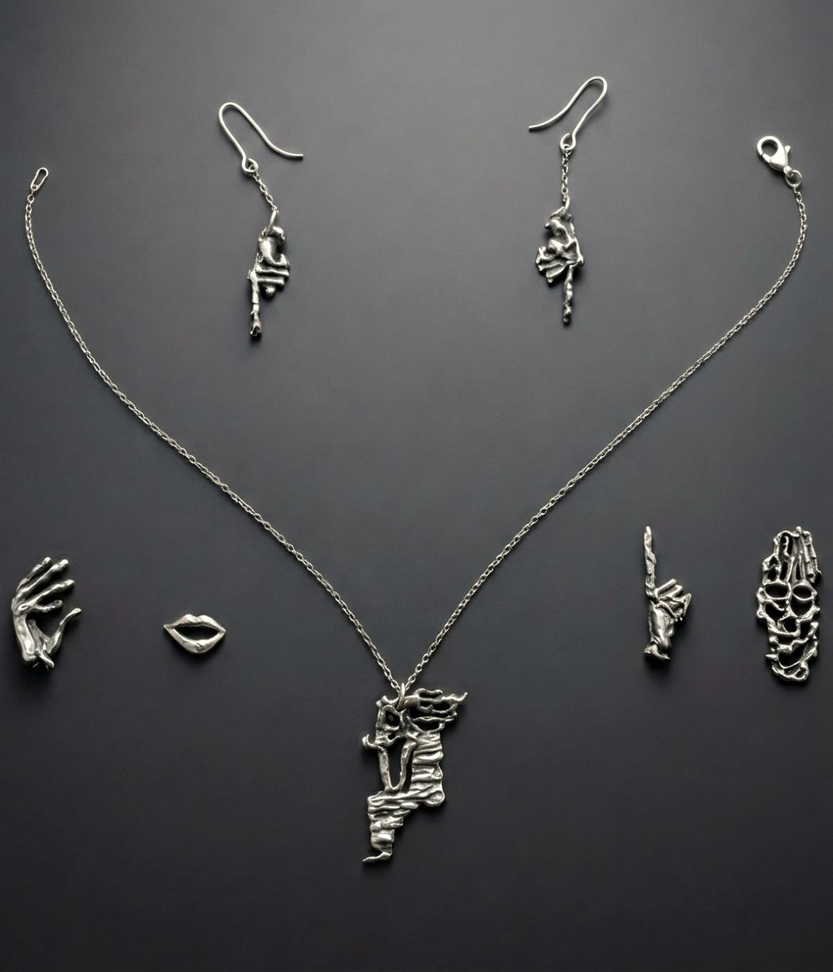 El conjunto DavXmoM sobre fondo gris: collar, pendientes y colgantes con forma de mano y de labios.