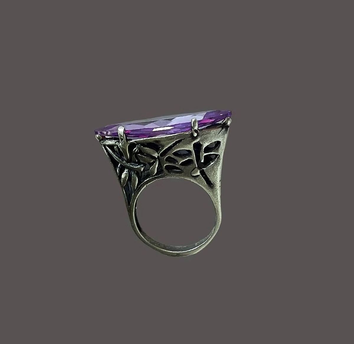 Anillo con amatista marquesa y galería de libélula sobre fondo ciruela.