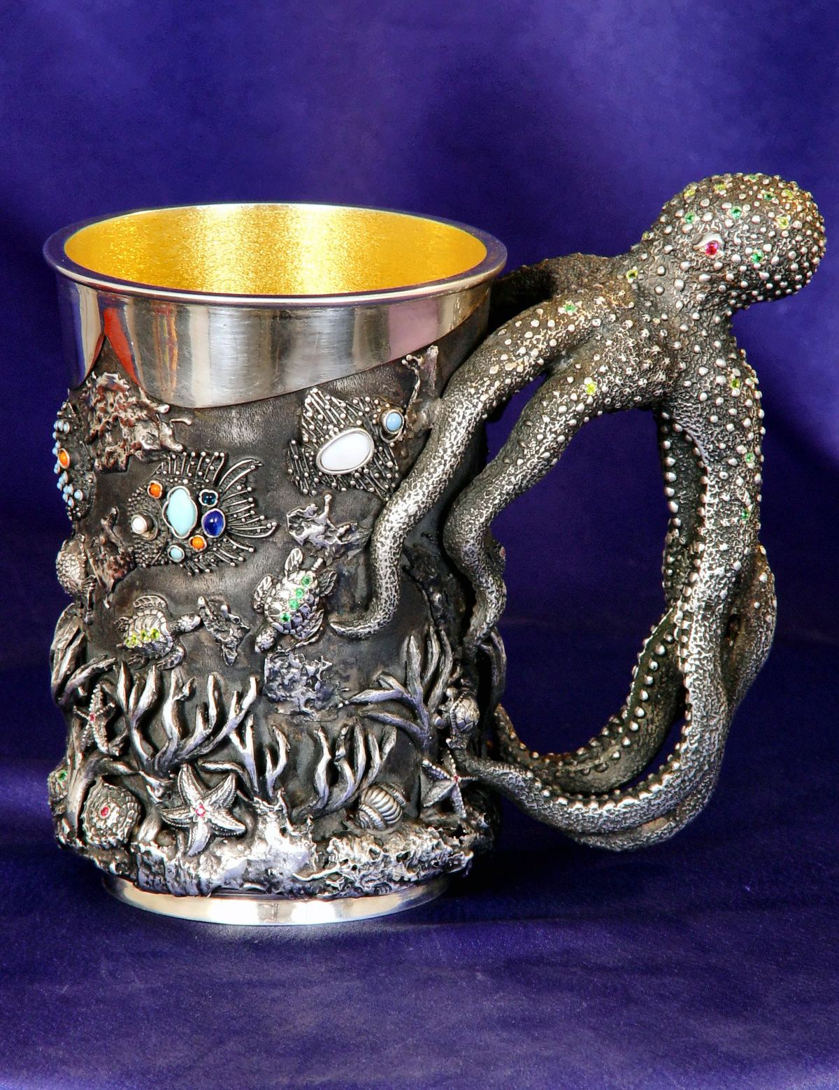 Jarra de plata con asa en forma de pulpo, sobre tela morada.