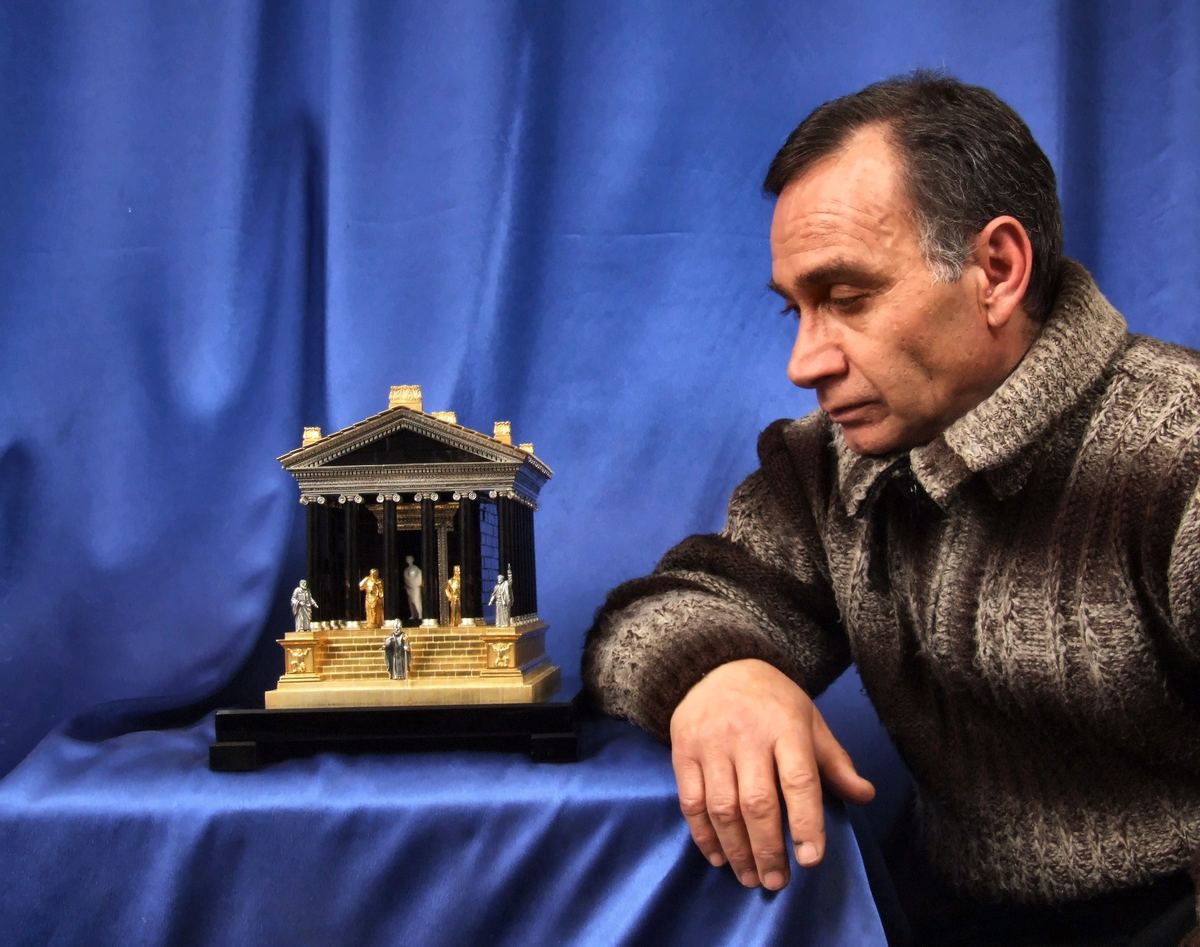 Samvel Hakobyan sentado junto a su maqueta del templo de Garni.