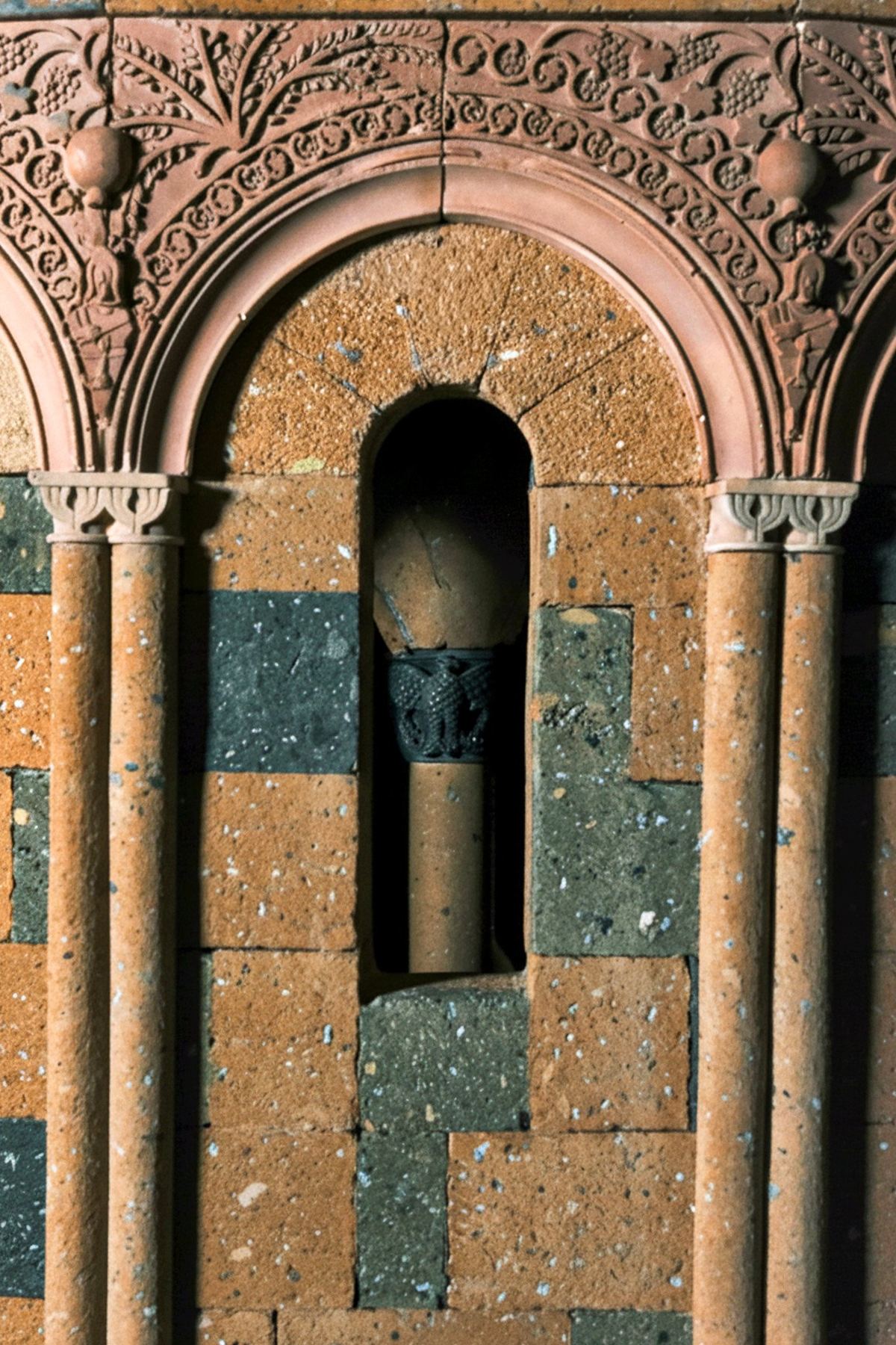 Detalle de un arco de piedra tallado a mano en la maqueta de toba de la catedral de Zvartnots.