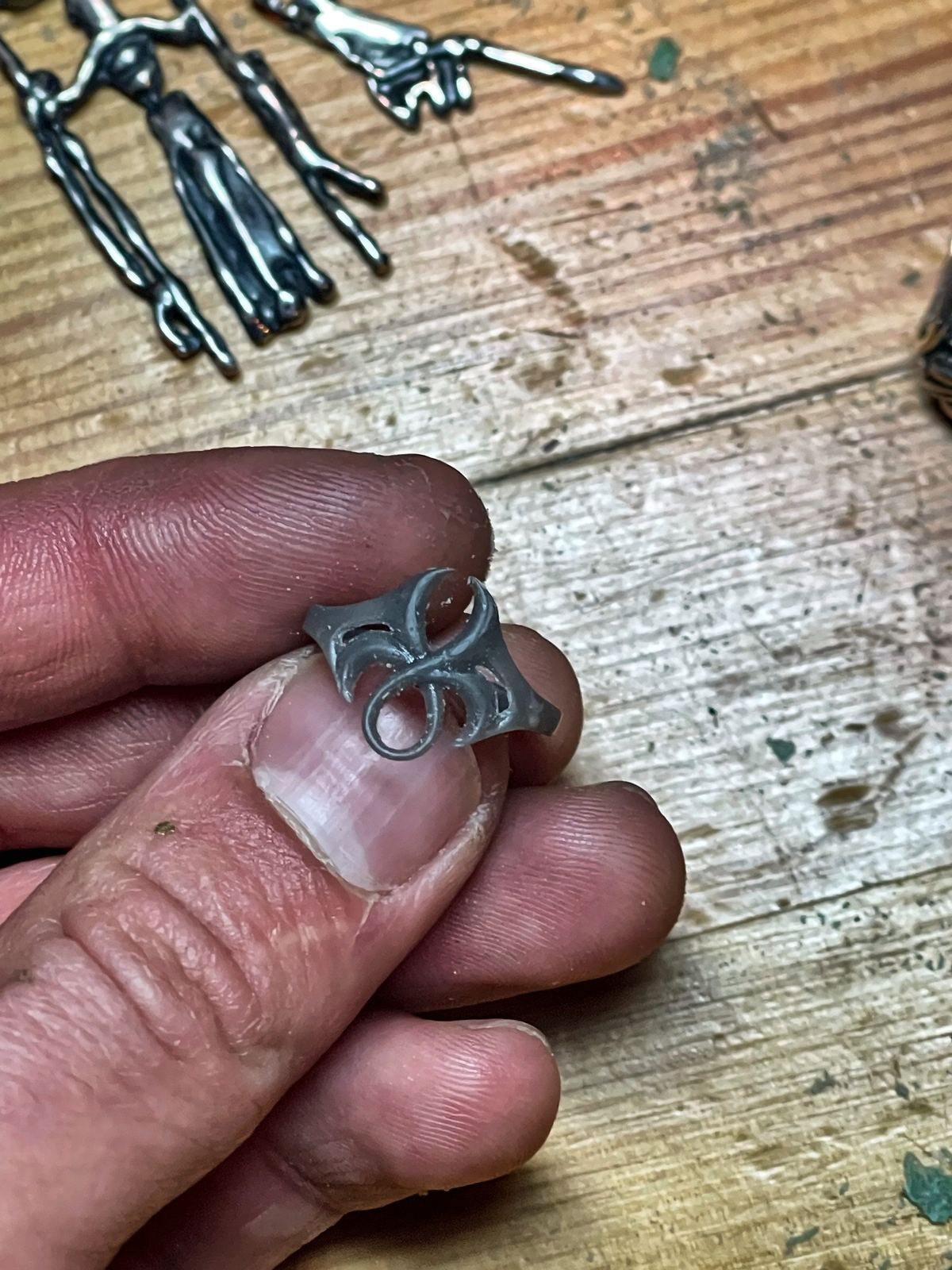 Modelo maestro impreso de un anillo de ornamento, sostenido entre los dedos (proceso, no es una pieza a la venta).